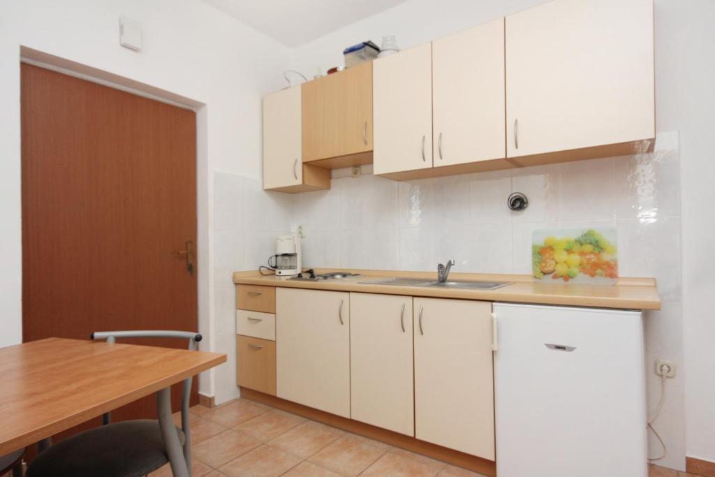 a kitchen with white cabinets and a wooden table at Apartments with a parking space Bibinje, Zadar - 5753 in Bibinje