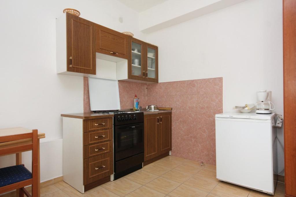 a kitchen with wooden cabinets and a stove and a refrigerator at Apartments with a parking space Bibinje, Zadar - 5753 in Bibinje