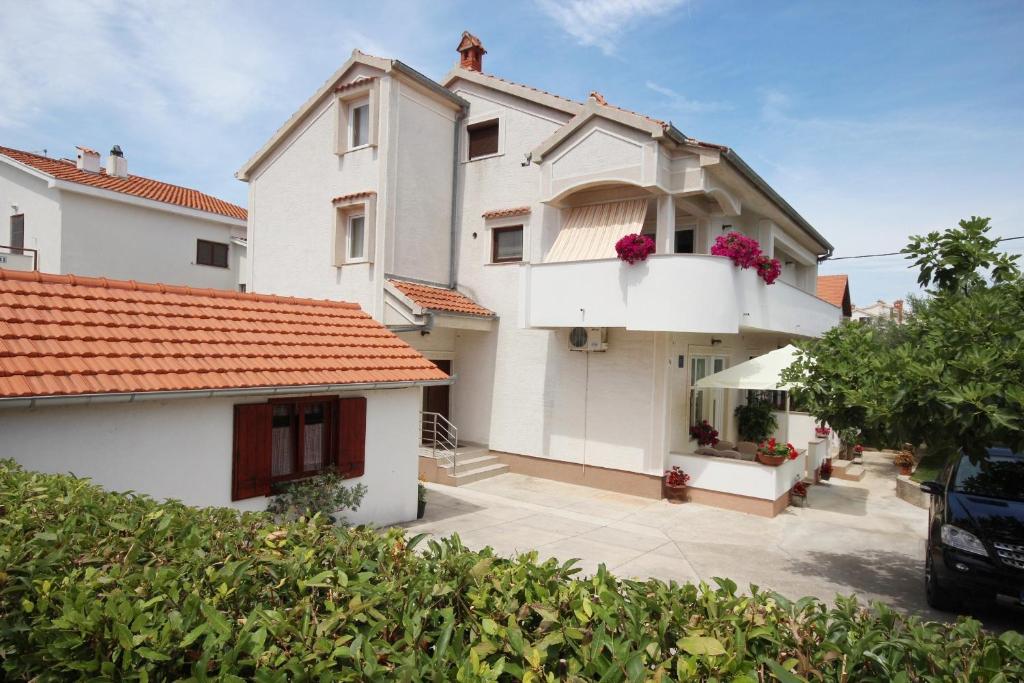 una casa bianca con fiori rosa sul balcone di Apartments with a parking space Zadar - Diklo, Zadar - 5875 a Zara (Zadar)