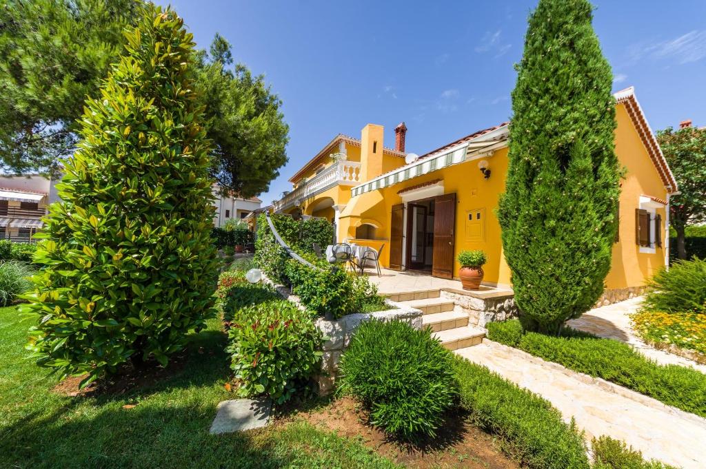 ein gelbes Haus mit Bäumen und Sträuchern in der Unterkunft Apartments with parking spaces Zadar - Diklo, Zadar - 5809 in Zadar