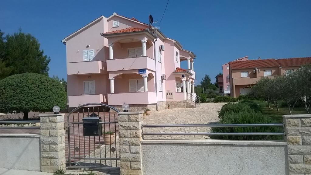 une maison rose avec une clôture devant elle dans l'établissement Apartments by the sea Vrsi - Mulo, Zadar - 5860, à Nin