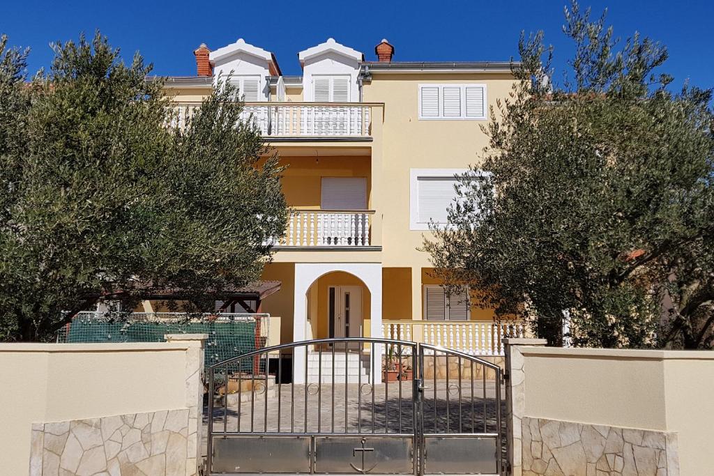 ein großes gelbes Haus mit Bäumen davor in der Unterkunft Apartments with a parking space Vrsi - Mulo, Zadar - 5796 in Vrsi