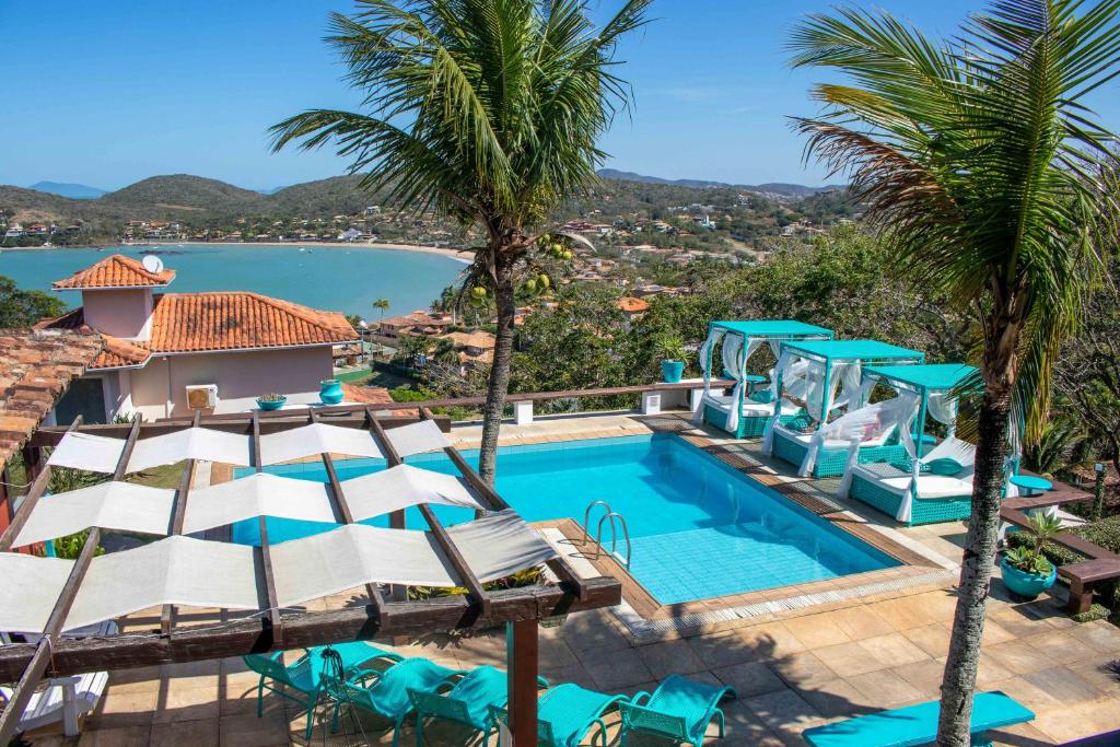 a pool with chairs and palm trees next to a resort at Royal Turquesa Boutique Hotel in Búzios