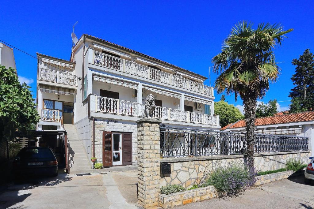 ein weißes Gebäude mit einem Balkon und einer Palme in der Unterkunft Apartments and rooms by the sea Zadar - 5874 in Zadar