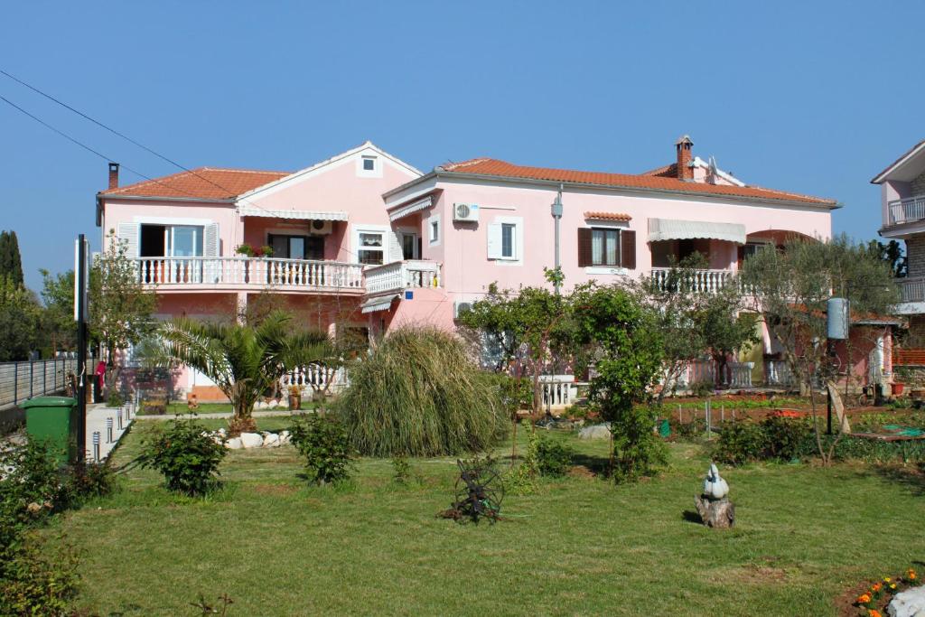 een roze huis met een hond in de tuin bij Apartments by the sea Sukosan, Zadar - 5905 in Sukošan