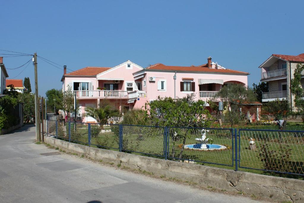 une clôture devant une maison rose dans l&#39;établissement Apartments by the sea Sukosan, Zadar - 5905, à Sukošan