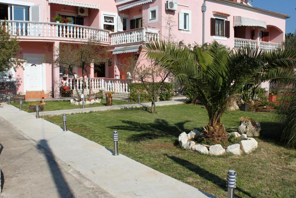 un palmier devant une maison rose dans l&#39;établissement Apartments by the sea Sukosan, Zadar - 5905, à Sukošan
