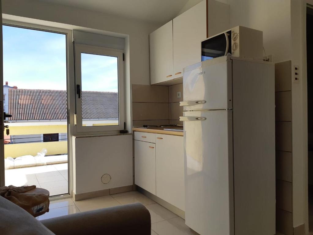 a kitchen with a white refrigerator and a window at Apartments by the sea Vrsi - Mulo, Zadar - 5859 in Vrsi