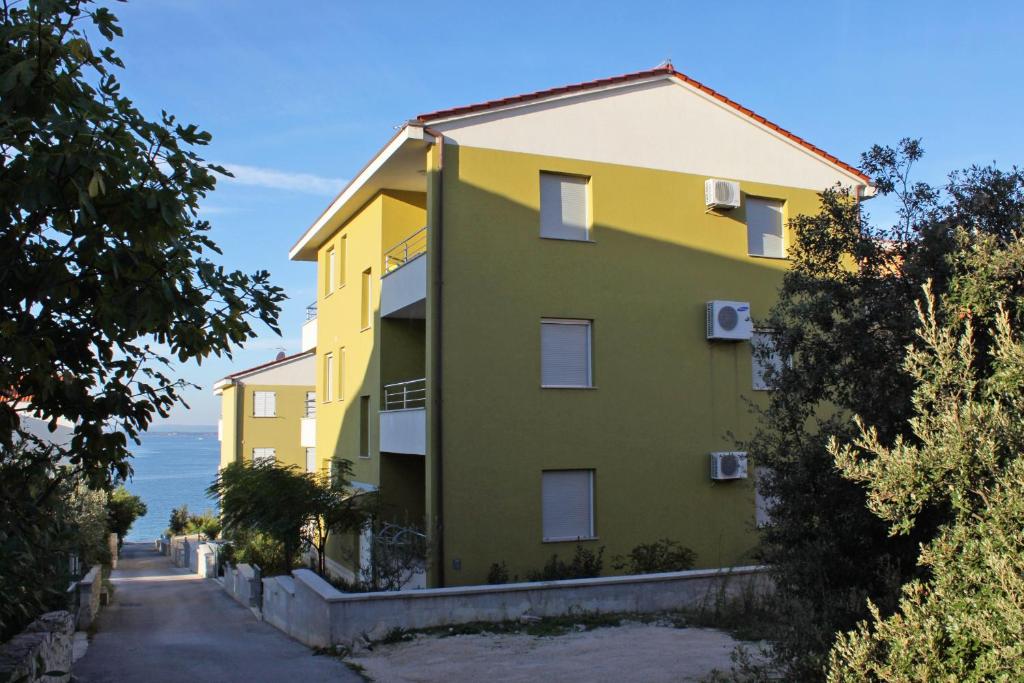 un bâtiment jaune et vert sur le côté d'une route dans l'établissement Apartments by the sea Kozino, Zadar - 5755, à Petrčane