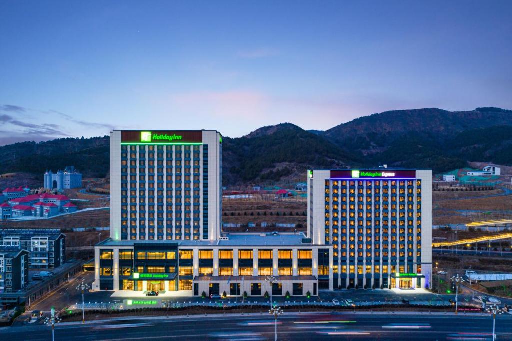 dwa wysokie budynki w mieście w nocy w obiekcie Holiday Inn Express Chengde Park View, an IHG Hotel w mieście Chengde