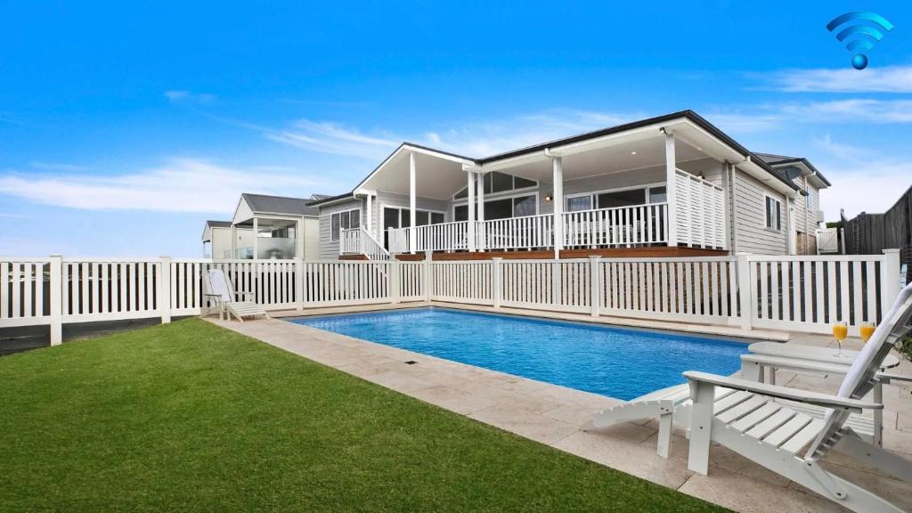 a house with a white fence and a swimming pool at Elm Cottage in Berry
