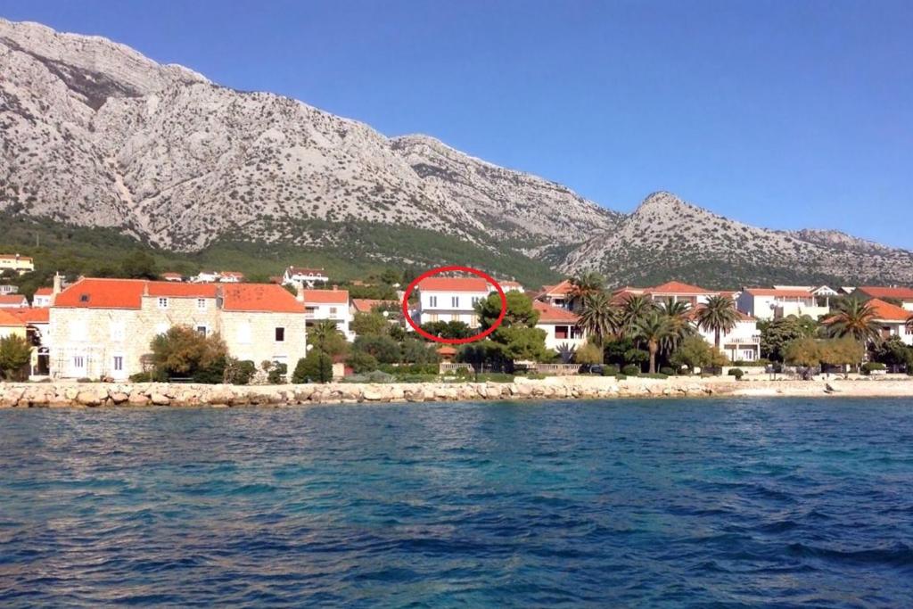 a group of houses on a beach with mountains in the background at Apartments and rooms by the sea Orebic, Peljesac - 4563 in Orebić