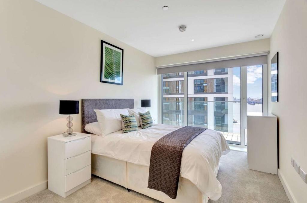 a bedroom with a bed and a large window at Riverside apartment minutes from Elizabeth line in London