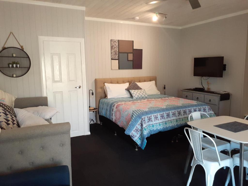 a bedroom with a bed and a table and a couch at Bluegrass BnB in Bundaberg