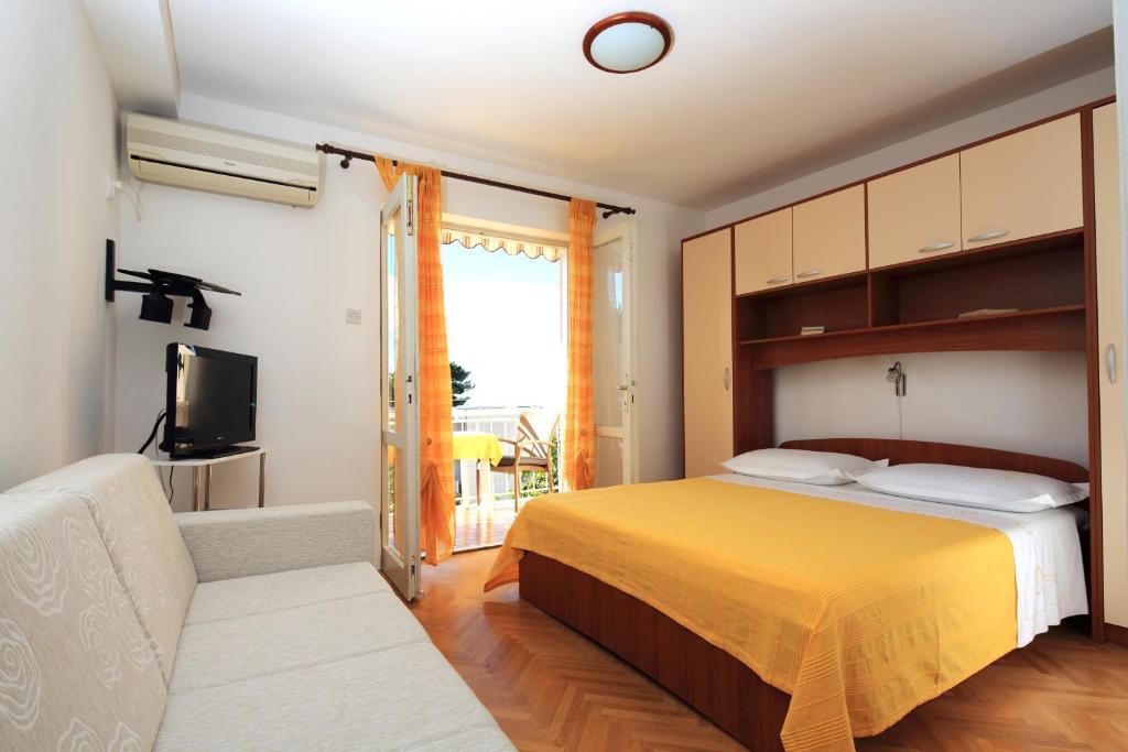 a bedroom with a bed and a couch and a television at Apartments by the sea Podgora, Makarska - 4332 in Podgora