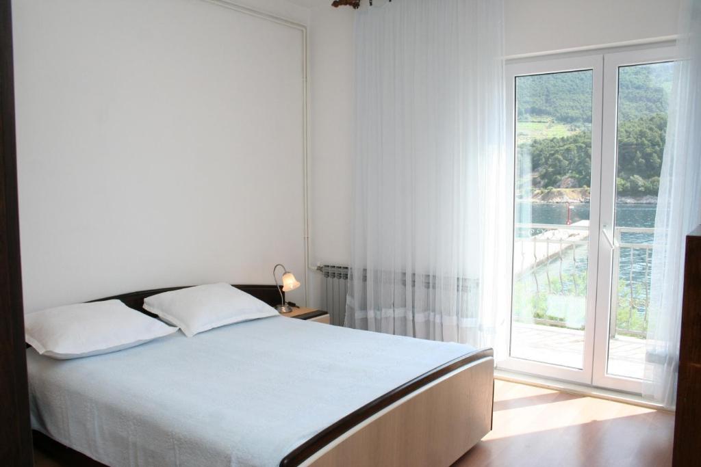 a white bedroom with a bed and a large window at Double Room Trstenik 4566b in Trstenik