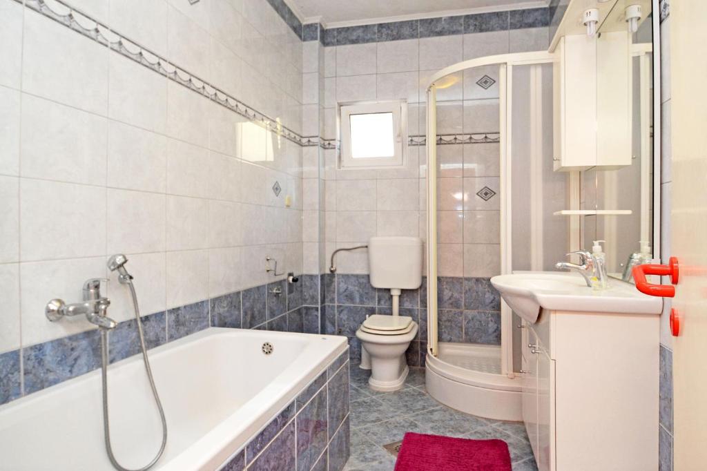 a bathroom with a tub and a toilet and a sink at Apartments by the sea Brna, Korcula - 4425 in Smokvica