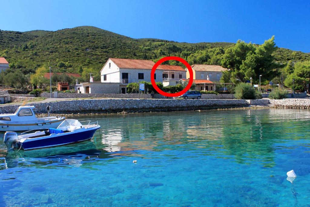 a red circle sitting in the water next to a boat at Apartments by the sea Kneza, Korcula - 4371 in Pupnat