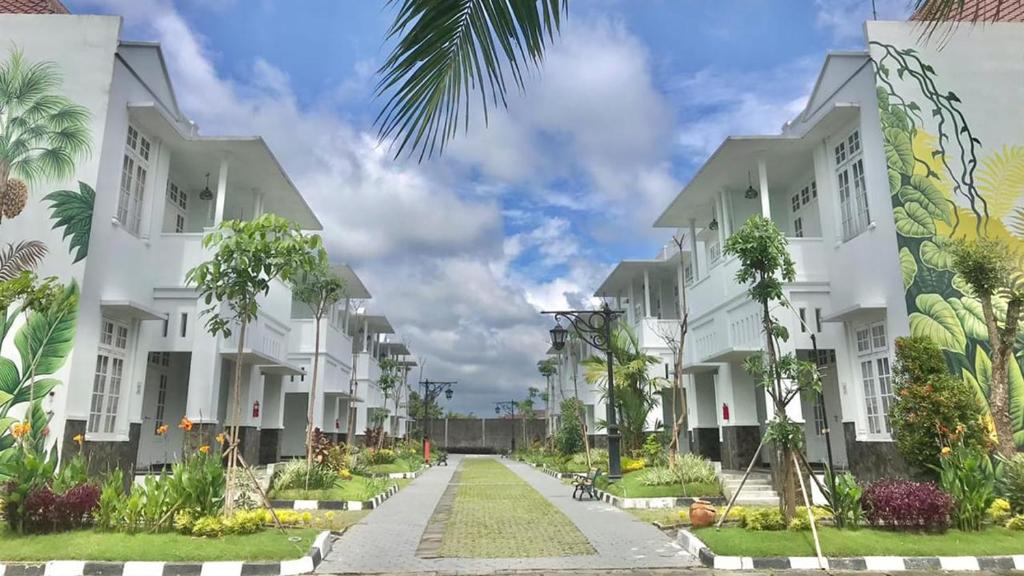 a row of white apartment buildings with palm trees at Al Azhar Azhima Hotel Resort and Convention in Solo