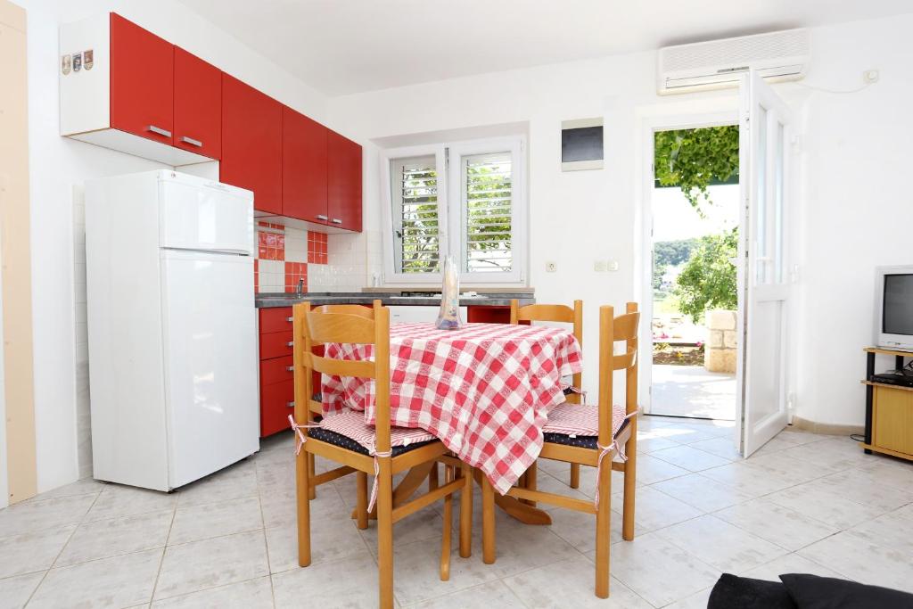 kuchnia ze stołem i krzesłami oraz białą lodówką w obiekcie Apartments with a parking space Lumbarda, Korcula - 4429 w mieście Lumbarda