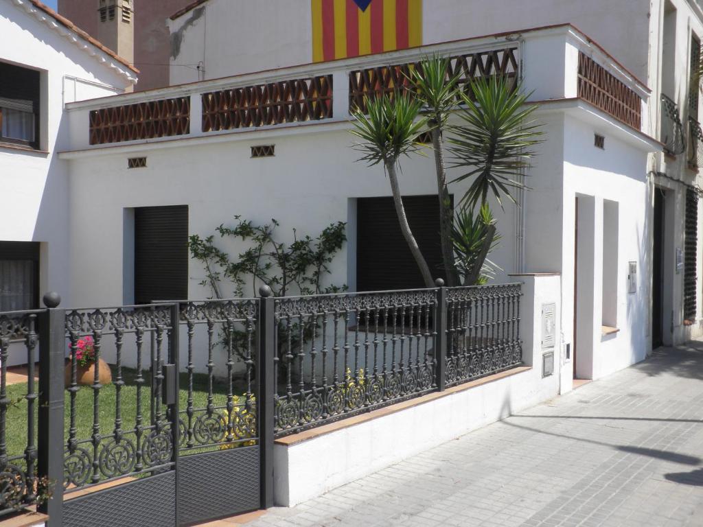 een wit gebouw met een zwart hek en een palmboom bij Apartament Can Batlle in Premiá de Mar