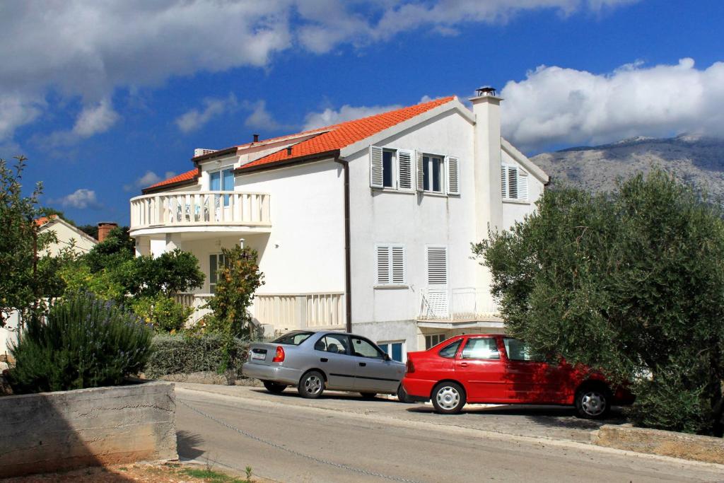 zwei Autos, die vor einem weißen Haus geparkt sind in der Unterkunft Apartments with a parking space Korcula - 4433 in Korčula
