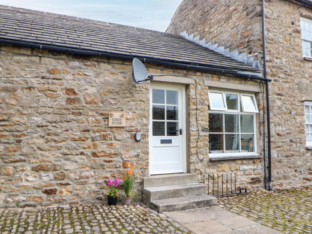 a stone house with a white door and a window at Kings Studio in Reeth