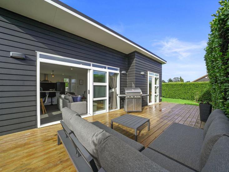 a outdoor patio with a couch and a grill at Treasure on Tuscan - Martinborough Holiday Home in Martinborough 