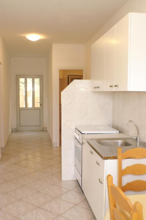 kuchnia z białymi szafkami, zlewem i stołem w obiekcie Apartment Grscica 4487a w mieście Prižba