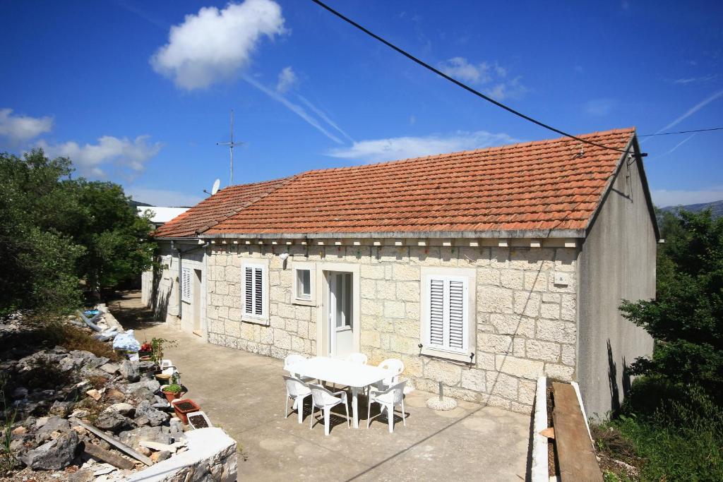 ein kleines Haus mit einem Tisch und Stühlen davor in der Unterkunft Rooms with a parking space Lumbarda, Korcula - 4436 in Lumbarda