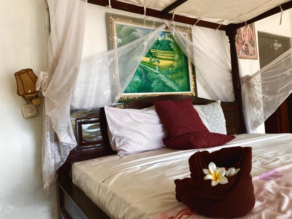 a bedroom with a canopy bed with red and white pillows at sriganesh in Ambat
