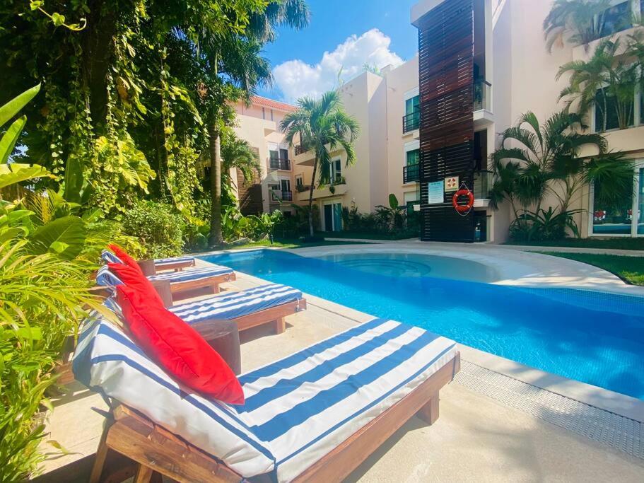 a swimming pool with two lounge chairs next to a building at Villa Tendenza Condo in Playa del Carmen