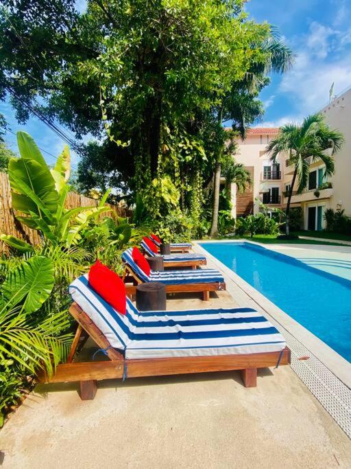 a row of lounge chairs next to a swimming pool at 5th AVENUE oasis 8 personas in Playa del Carmen