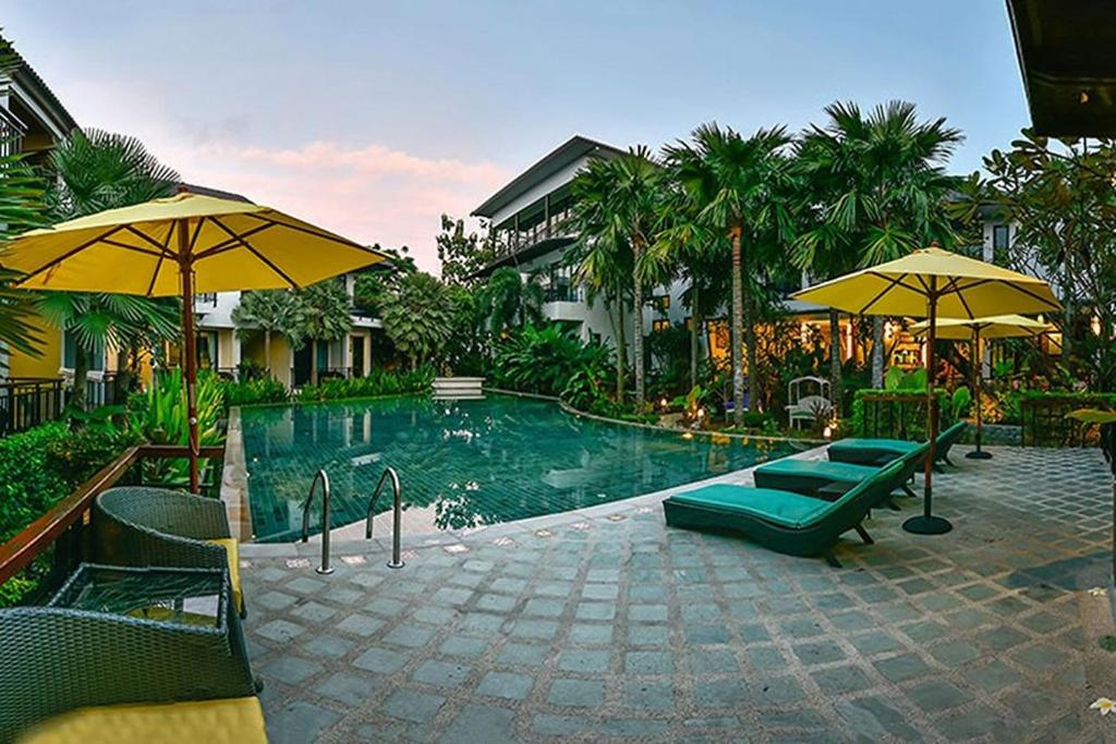 a pool with chairs and umbrellas in a resort at Coco Retreat Phuket Resort and Spa - SHA Plus in Chalong 