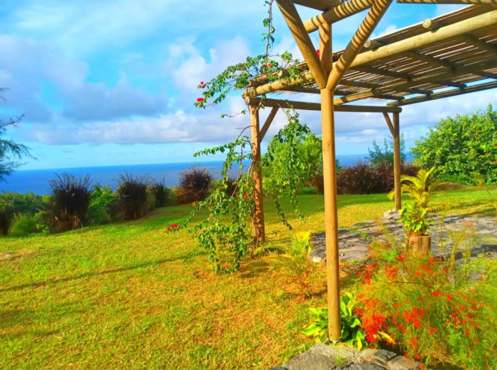 einen Garten mit einer Pergola und dem Meer im Hintergrund in der Unterkunft COCO MANGO Villa in Trèfles