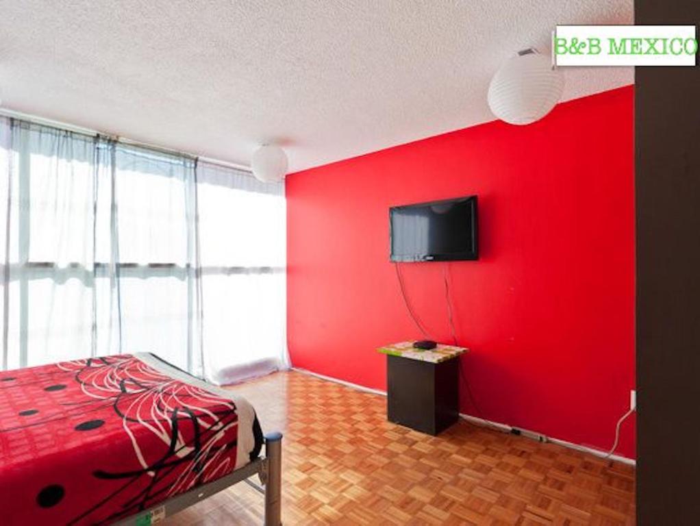 um quarto vermelho com uma cama e uma televisão na parede em B&B México Roma Norte em Cidade do México