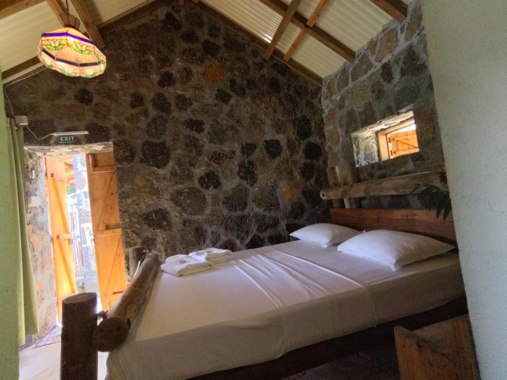 a bedroom with a bed with a stone wall at La Case Du Pecheur in Grand Sable