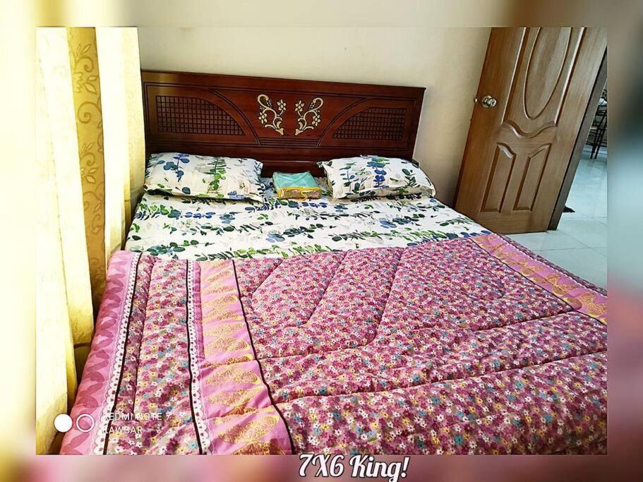 ein Bett mit einer Decke und Kissen darauf in der Unterkunft DAC Peaceful AC King Bed WIFI & 24hr Security in Dhaka