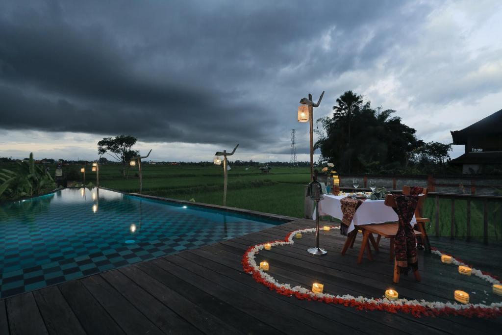 een zwembad met een tafel en stoelen op een houten terras bij Maha Shanti Ubud Villa in Ubud