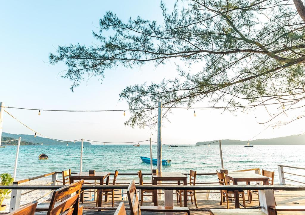 a row of wooden tables and chairs on the beach at Sara Resort in Koh Rong Sanloem
