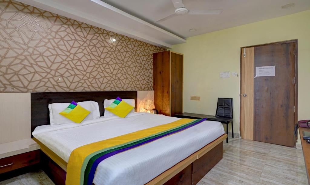 um quarto com uma grande cama branca com almofadas amarelas em Itsy By Treebo - Galaxy Park em Shamshabad