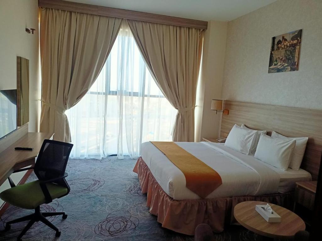 a hotel room with a bed and a desk and a window at Grand Tourist Hotel in Muscat