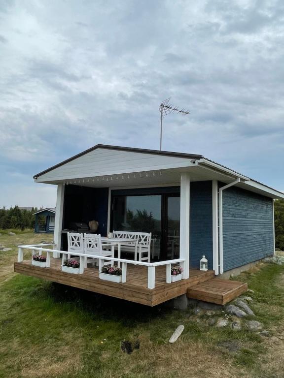 une petite maison avec une terrasse couverte et 2 chaises blanches dans l'établissement Künkaotsa, à Värati