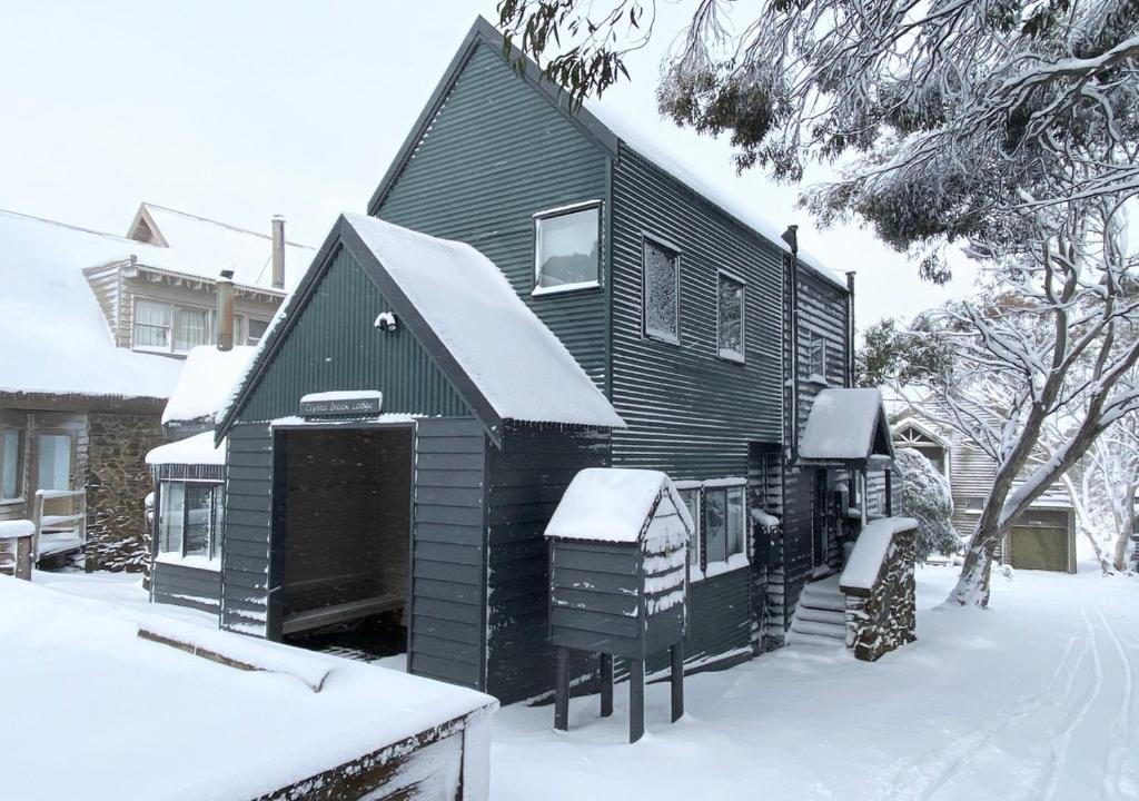 a black house with snow on top of it at Crystal Brook Lodge in Dinner Plain