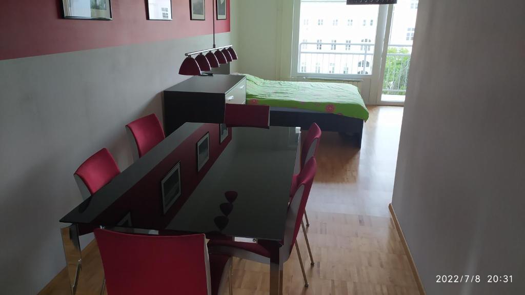 a dining room table with red chairs in a room at city center park view appartment in Maribor