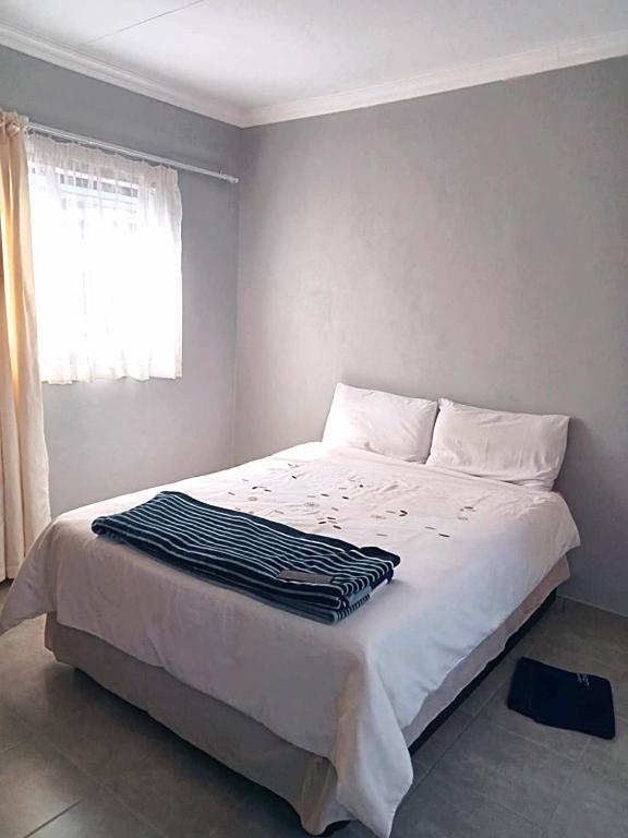 a bedroom with a bed with a black and white blanket on it at Rethapaki Guesthouse in Secunda