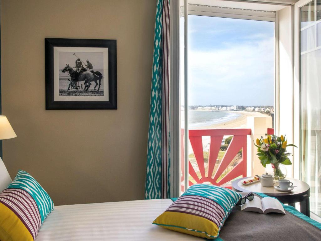 a bedroom with a bed with a view of the beach at Hotel Mercure La Baule Majestic in La Baule
