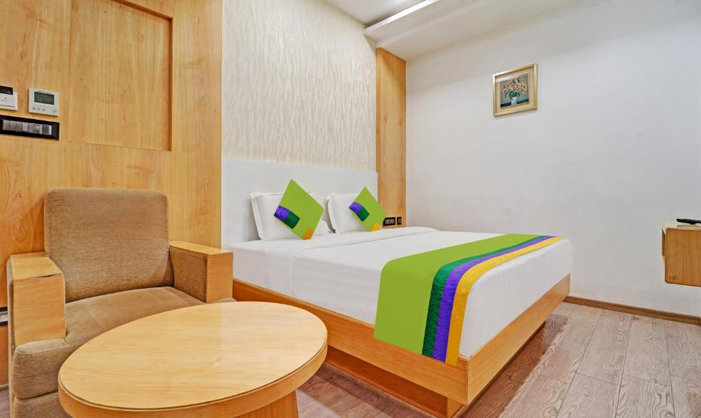 a bedroom with a bed and a chair and a table at Treebo Trend Vinayak Inn, Near Railway Station in Coimbatore
