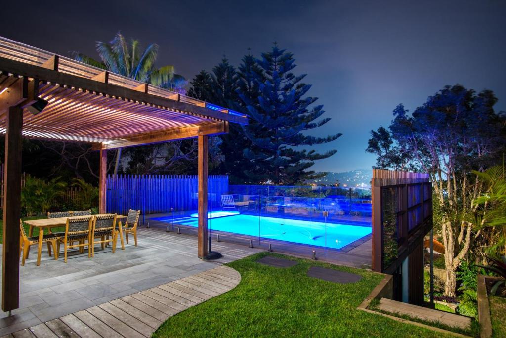eine Terrasse mit einem Tisch und einem Pool in der Nacht in der Unterkunft Turimetta Beach House in Warriewood
