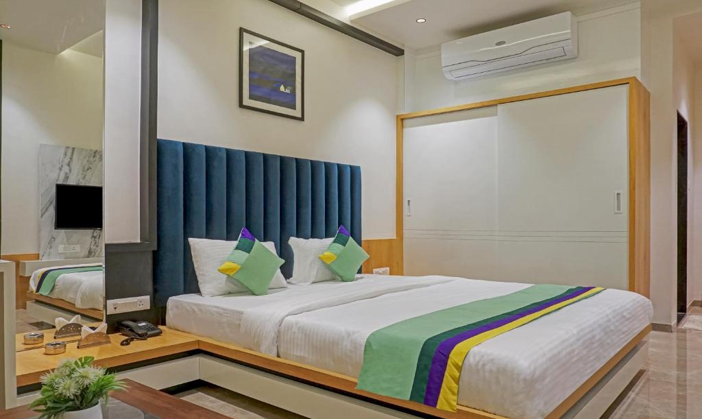 a bedroom with a large bed with a blue curtain at Treebo Trend The Utsav, Nashik in Nashik